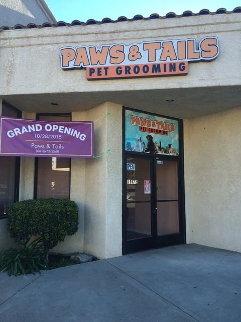 Exterior of Paws & Tails pet grooming storefront with grand opening sign dated 10/28/2015