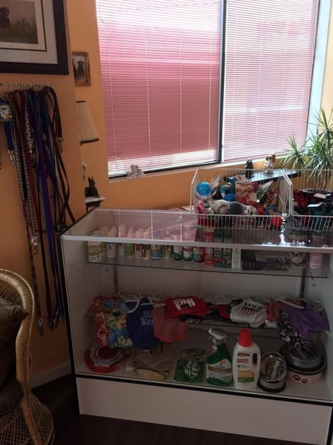 Display case containing beauty and personal care products in bedroom with orange walls and pink blinds